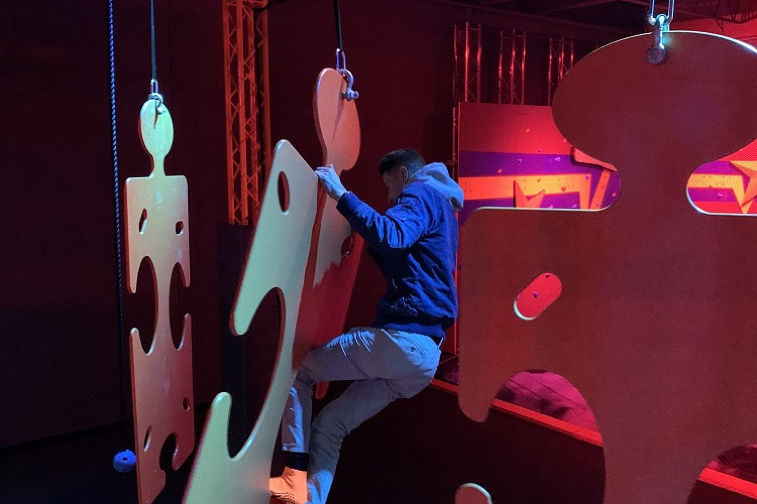 a person hangs on a giant puzzle piece at the ninja obstacle course at k1 speed mount kisco