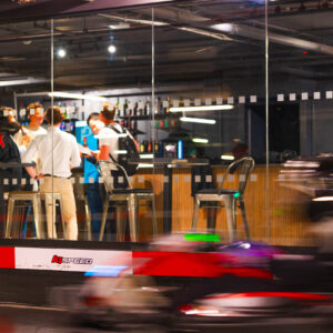 go karts race by while people party behind glass walls at k1 speed in london